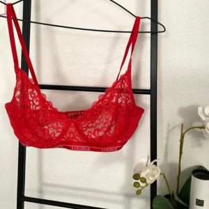 Röd spets bralette  Lounge Underwear  - Säljer en röd spets bh / bralette från Lounge med tunna axelband och elastiskt band under bysten i storlek 80E. Endast använd två gånger så är i väldigt fint skick🩷