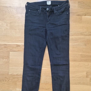 Mörkblå skinny jeans från Lee - Snygga mörkblå jeans från Lee med klassisk femficksdesign och skinny passform. Jeansen har dragkedja, Lee-logga på bakfickan och är tillverkade i stretchig denim för en bekväm känsla. Perfekta till sneakers eller boots.