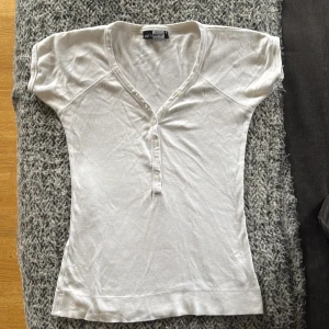 Vit topp med v-ringning  - Vit topp från Tutti Frutti med v-ringning och knappar framtill. Tröjan är kortärmad och sitter jättesnyggt sitter snyggt. Storleken är S och haft på mig max 2 gånger så skicket är i 10/9.