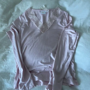 Ljusrosa långärmad topp med spets - Supersöt ljusrosa långärmad topp från Gina Tricot med v-ringning och fina spetsdetaljer runt halsen. Mjuk och skön i bomullsmix. Tyvärr för kort och bara använd 1 gång 💖