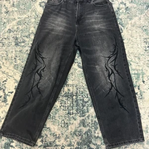 Svarta wide jeans från House - Svarta jeans från House i modell Skater med bred passform och tribal-inspirerat mönster längs benen. Jeansen har raka ben, två bakfickor och coolt sliten tvätt. Perfekta för dig som gillar streetstyle och vill sticka ut.RIKTIGT BAGGY