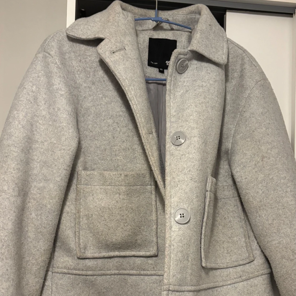 Ljusgrå kappa med stora fickor