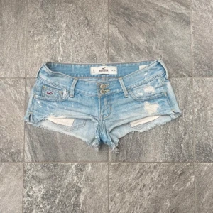Ljusblå jeansshorts från Hollister - Snygga ljusblå jeansshorts från Hollister med slitna detaljer, midjemåttet är ca 36 cm