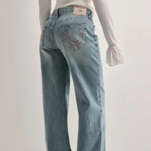 True Religion wide jeans ljusblå - Säljer mina True Religion jeans från Nelly!! Ljusblå med röda detaljer på bakfickorna samt på vissa sömmar. Jättecoola men kommer tyvärr inte till användning för mig💜💜🙌🏽🌺De är använda en gång och nypris är 1300kr (jag är 175cm lång och strl är 28) 