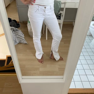 Vita jeans med slits från Zoul - Snygga vita jeans från Zoul med raka ben och slits nertill. Klassisk femficksmodell med dragkedja och knapp framtill. Jeansen har midwaist passform och är tillverkade i bomull med lite stretch för extra komfort.