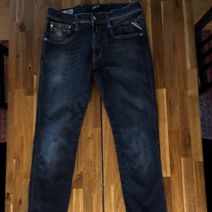 Mörkblå Replay anbass - Snygga mörkblå jeans från Replay med klassisk femficksdesign och coola kontrastsömmar på bakfickorna. Jeansen har en slim passform och är tillverkade i stretchig denim för extra komfort. Perfekta för dig som gillar en modern och stilren look. Endast använda ett fåtal gånger!