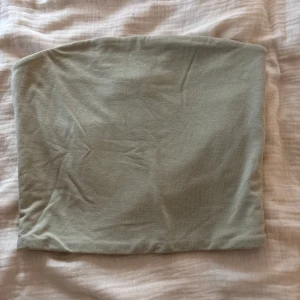 Grön tubtopp från Bik Bok - Snygg grön tubtopp från Bik Bok i storlek XS. Enkel och stilren design med bandeauform och mjukt stretchigt material som sitter skönt. Perfekt att matcha med jeans eller kjol för en clean look.