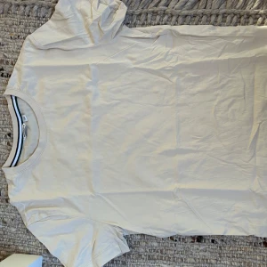 Björn borg beige t-shirt i bomull - En stilren beige t-shirt från Björn borg i mjuk bomull. T-shirten har rund halsringning med en diskret randig detalj på insidan av kragen och korta ärmar. Perfekt basic-plagg att matcha med jeans eller shorts.