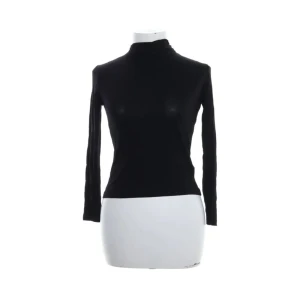 Tunn polotröja från H&M - Svart polotröja o tunt tyg med smal passform. Tröjan har en hög krage och en liten knappdetalj med öppning i nacken. Perfekt att styla med jeans eller kjol för en clean sleek look.