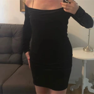 Svart sammetsklänning 77thFLEA L - Svart sammetsklänning från 77thFLEA i storlek L. (Upplever att den passar bättre på en M). Klänningen har lång ärm, offshoulder-ringning och är kort i modellen. Materialet är mjuk och stretchig polyesterblandning som ger en snygg passform och lyxig känsla.