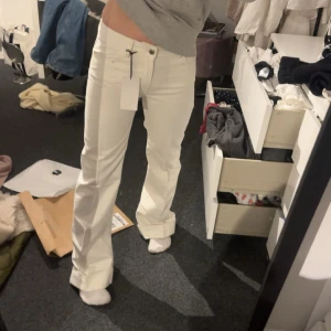 Vita wide jeans från Zara - Snygga vita jeans med wide fit och pressveck. Byxorna har låg midja, raka ben och klassisk stängning med knapp och dragkedja. Perfekta för en clean och stilren look. . Slutsålda! Lite skitiga men går nog bort i tvätten 