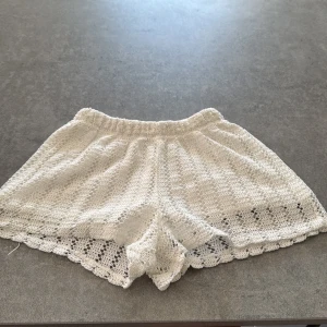 Vita virkade shorts från Zara - Superfina vita virkade shorts från Zara med elastisk midja och innerbyxa i mjuk bomull. Shortsen har ett snyggt virkat mönster och vågig kant nertill, perfekta för sommardagar. Lätta att matcha med en enkel topp eller linne. Det är inbyggda shorts innanför det virkad.