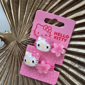 Hello Kitty rosa hårsnoddar - Söta rosa hårsnoddar med Hello Kitty-huvuden. Varje snodd har också en genomskinlig rosa blomma. Perfekt accessoar för dig som älskar kawaii och vill ha något gulligt i håret.