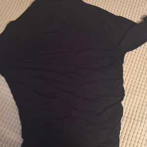 Svart långärmad tröja 157 Black Label - En stilren svart långärmad tröja från 157 Black Label Collection. Tröjan har en klassisk passform och är tillverkad i ett mjukt och lätt material som passar perfekt till lager-på-lager. Enkel design utan synliga detaljer eller mönster.