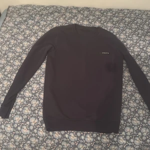 Svart långärmad tröja från Prada - Säljer en stilren svart långärmad tröja från Prada med diskret logga på bröstet. Tröjan har rund halsringning och en clean look som passar perfekt till jeans eller dressade byxor. Materialet känns mjukt och bekvämt mot huden.