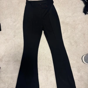 Svarta kostymbyxor bootcut - Snygga svarta kostymbyxor med hög midja och bootcut-ben. Klassisk design med pressveck framtill och knappstängning i midjan. Vet ej om dom är XS eller S men dom bör passa båda👍🏻