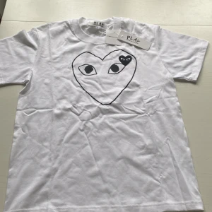 Vit Comme des Garçons Play t-shirt - Snygg vit t-shirt från Comme des Garçons Play i storlek S med hjärtmotiv på bröstet. Slim passform, korta ärmar och rund halsringning. Passar någon som är mellan 173-177 cm lång. Priset går självklart att diskutera. Hör av dig vid intresse!