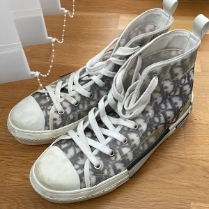 Mönstrade sneakers från Dior - Snygga höga sneakers från Dior med ett unikt mönster i grått och vitt.Skorna är lite smutsiga och därför sänker jag priset för det med dock är det enkelt att ta bort men jag är ju så lat. Skorna är helt äkta och jag har fått de i present av en före detta allsvensk fotbollsspelare. 