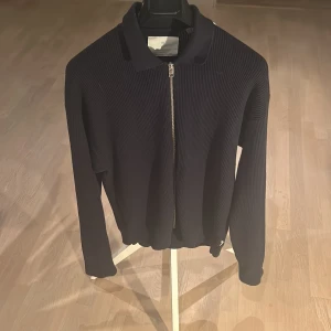 Marinblå tröja från Jack & Jones - Säljer en stilren marinblå ribbad tröja från Jack & Jones med dragkedja framtill. Tröjan har långa ärmar och en klassisk krage. Perfekt för en trendig look. Nypris 699 kr, mitt pris 149 kr. Hör av dig vid frågor eller funderingar. Priset är ej hugget i sten så kom med bud!😀