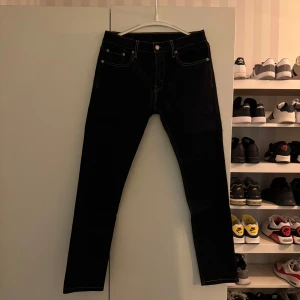 Svarta jeans från Levi's - Snygga svarta 512 jeans från Levi's med klassisk femficksdesign och kontrastsömmar. Perfekta för en stilren look. Passar till många olika tillfällen. Byxorna är nya utan kvitto. Byxorna är i nyskick. Det är en slimmodell. Storlek, 30-32.