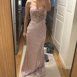 Ljusrosa balklänning med spetsdetaljer - Elegant ljusrosa långklänning med smala axelband och spetsdetaljer på överdelen. Klänningen har en glittrig finish och en vacker öppen rygg. Perfekta balklänningen! 💞💓💗💕🩷köptes för 1900kr