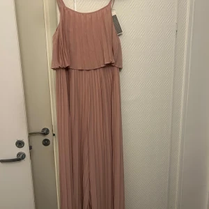 Rosa jumpsuit från Vila - Säljer en elegant rosa jumpsuit från Vila med smala axelband och plisserad design. Perfekt för en stilren look. Aldrig aldrig med prislapp kvar som ni kan se☺️🌸