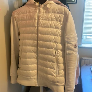 Vit Cardigan från Moncler - Säljer en stilren vit Cardigan från Moncler. Säljer denna för att den börjar bli för liten. Den är i bra skick bara att monclear lappen i nacken sitter löst på ena sidan men det går lätt att sy ihop och den sitter redan rätt hårt. Storlek S