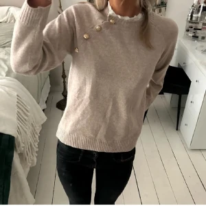 Beige stickad tröja med knappar - Säljer en mysig beige stickad tröja med  knappar på axeln. Tröjan har en  fin krage😍jag säljer då den inte kommer till användning längre 💓💓