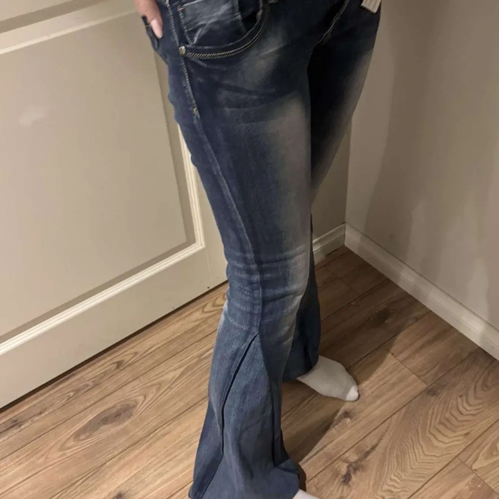 Snygga blå bootcut jeans med låg midja och en lätt tvättad look. Omsydda. Midjemått: 36,5 cm Grenmått: 19 cm Innerbenslängd: 82 cm. Farkut & Housut.