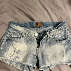 Lågmidjade jeansshorts med slitningar - Säljer ett par lågmidjade ljusblå jeansshorts med slitningar från gina tricot i storlek 34. Använd några gånger 