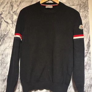 Moncler Sweatshirt  - Säljer denna svarta stickade tröjan från Moncler i storlek S men kan även passa M!! Den är äkta och i ett bra skick 8/10 skulle jag sagt. Använd ett par gånger men inte mer än 15 gånger. Säljer för den blivit förliten. 