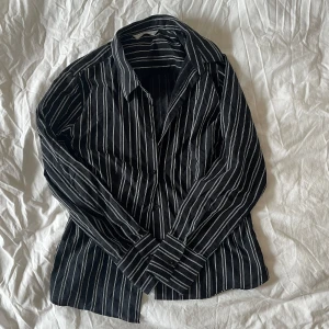 Randig skjorta - Svart skjorta med vita ränder. Från märket Amaranto, storlek M