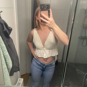 Vit linnetopp från bikbok - Säljer en söt vit linnetopp från bikbok. Toppen har en v-ringad design med knytning framtill och en lätt volangdetalj vid midjan. Perfekt för varma sommardagar! Har lite gula fläckar men inget man ser när man har på sig den som ni ser på bild 1. Går att pruta 