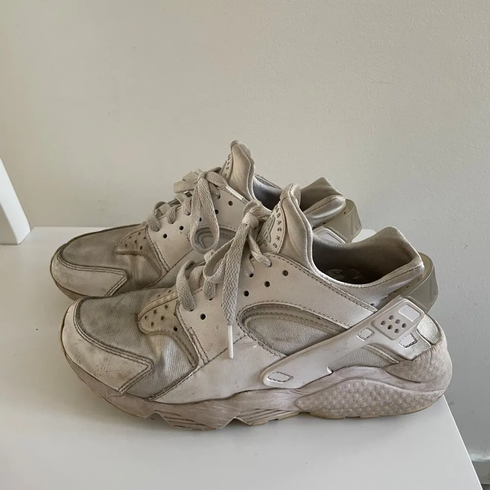 Säljer ett par vita Nike sneakers med snörning och rund tå. Skorna har en robust sula och är perfekta för en sportig look. De har en klassisk design med märkets logga på baksidan.. Kengät.