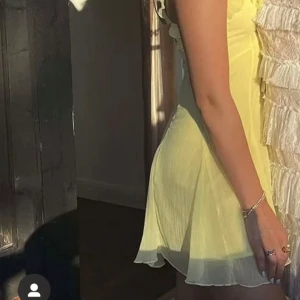 Gul mini klänning -  gul klänning med volangdetaljer och knytning framtill. Storlek XS från Gina Tricot.