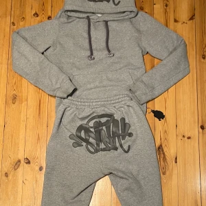 Synaworld tracksuit - Synaworld Tracksuit|Storlek: S passar 170-175|Skick: 7/10 därav att dragkedjan är sönder på vänster benet|Tillbehör: Hela Tracksuit + nyckelring |Nypris: 5 780 kr|Hör av er för ev frågor och bilder✔️. Priset kan diskuteras vid snabb affär!📋kan köpas separat‼️
