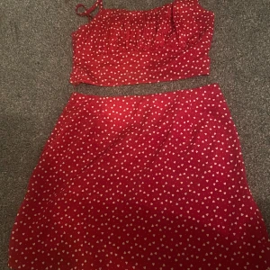 Röd kjol med hjärtmönster - Söt röd kjol med vita hjärtan. Perfekt för en romantisk look. Matchande topp finns också.