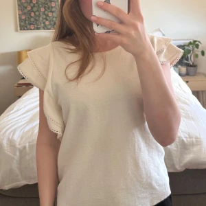 Vit topp med volanger  - Säljer en stilren krämvit topp med volangdetaljer på ärmarna, bara andvänd ett fåtal gånger🥰💕
