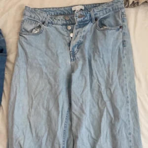 Ljusblå högmidjade jeans - Säljer ett par snygga ljusblåa jeans från Monki. Jeansen har en klassisk femficksdesign och knappar framtill. Perfekt för en avslappnad stil. Passar bra till både sneakers och sandaler.