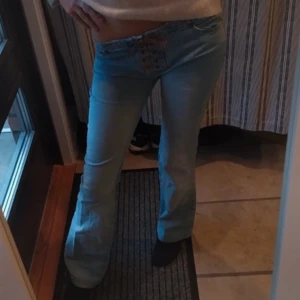 Unika bootcut jeans med snörning - Snygga blå lågmidjade bootcut jeans med unik snörning framtill. Perfekta för en trendig look. De har en lågmidjad passform som ger en avslappnad stil. Så så fina och sköna!! Skulle säga storlek s/xs