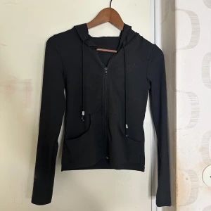 Svart hoodie med dragkedja - Snygg svart tajt hoodie med dragkedja och justerbar huva. Den har långa ärmar och praktiska fickor framtill 🖤