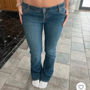 Blå bootcut jeans med broderade bakfickor - Säljer ett par  blå bootcut jeans med låg midja och broderade detaljer på bakfickorna. Jeansen stängs med dragkedja och knapp framtill. Hör av er vid frågor💗