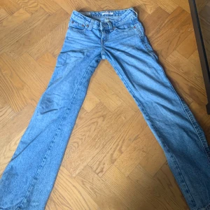 Blå bootcut jeans Noughties - Säljer ett par klassiska blå bootcut jeans från Noughties i storlek 24. Jeansen har fyra fickor, gylf med dragkedja och knapp samt snygga kontrastsömmar. Perfekta för dig som gillar retrostil och bootcut-modell.