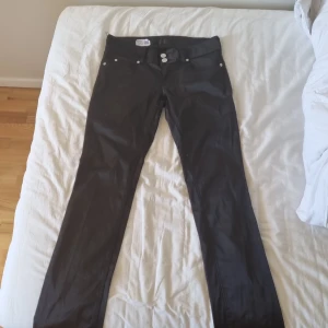 Svarta jeansbyxor från Gina Tricot - Säljer ett par svarta jeansbyxor från Gina Tricot med normal midja och raka ben. Byxorna har klassisk femficksdesign, silverfärgade knappar och dragkedja. Perfekta till många olika outfits.