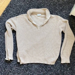 Beige stickad tröja med dragkedja från Grunt - Säljer en beige stickad tröja från Grunt i storlek M. Tröjan har en halv dragkedja vid kragen och är långärmad med ribbade muddar. Perfekt för lager-på-lager och enkel att matcha med olika outfits.