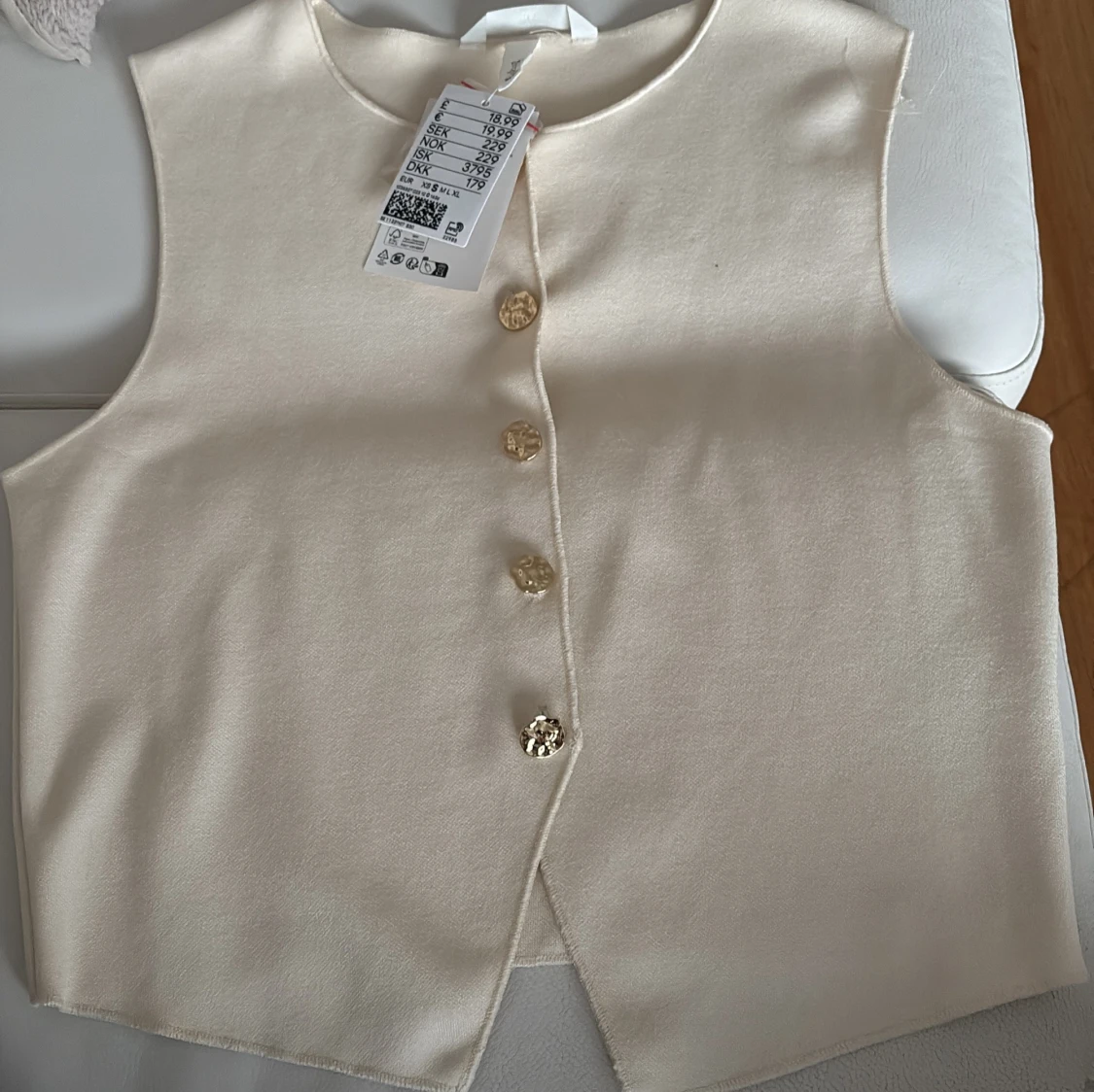 Krämvit väst med guldknappar