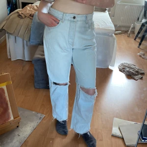 Ljusblåa jeans - Detta är mina högmidjade jeans med hål. Säljer för att de är för stora på mig. Är mycket stretchiga och funkar perfekt nu till våren! Har äkta fickor och ingen dragkedja