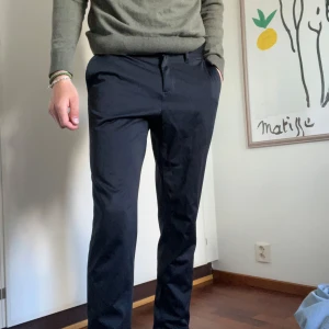 Svarta kostymbyxor från Michael Kors - Säljer ett par svarta kostymbyxor från Michael Kors i slim fit-modell. Byxorna har klassisk rak passform, diskreta fickor och stängs med dragkedja och knapp. Perfekta för en stilren look.