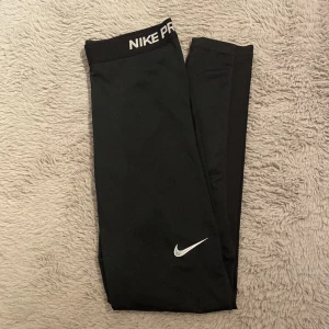 Svarta Nike Pro tights - Säljer ett par svarta Nike Pro tights med elastisk midja och vit logga. Använda men fortfarande bra skick. 🩷Obs Nike loggan på benet är slitet (bild 3)