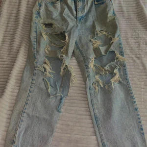 Ljusblå slitna jeans från New Look - Ljusblå jeans med kraftiga slitningar och fransade hål framtill. Extremt urtvättad färg. Modellen är slim fit och har klassisk femficksdesign. Perfekta för en edgy och avslappnad stil.